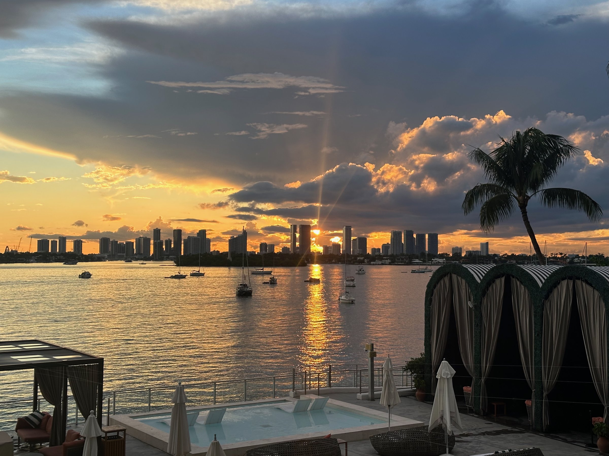 Building pool and marina at sunset with Biscayne Bay, boats, and palm tree
