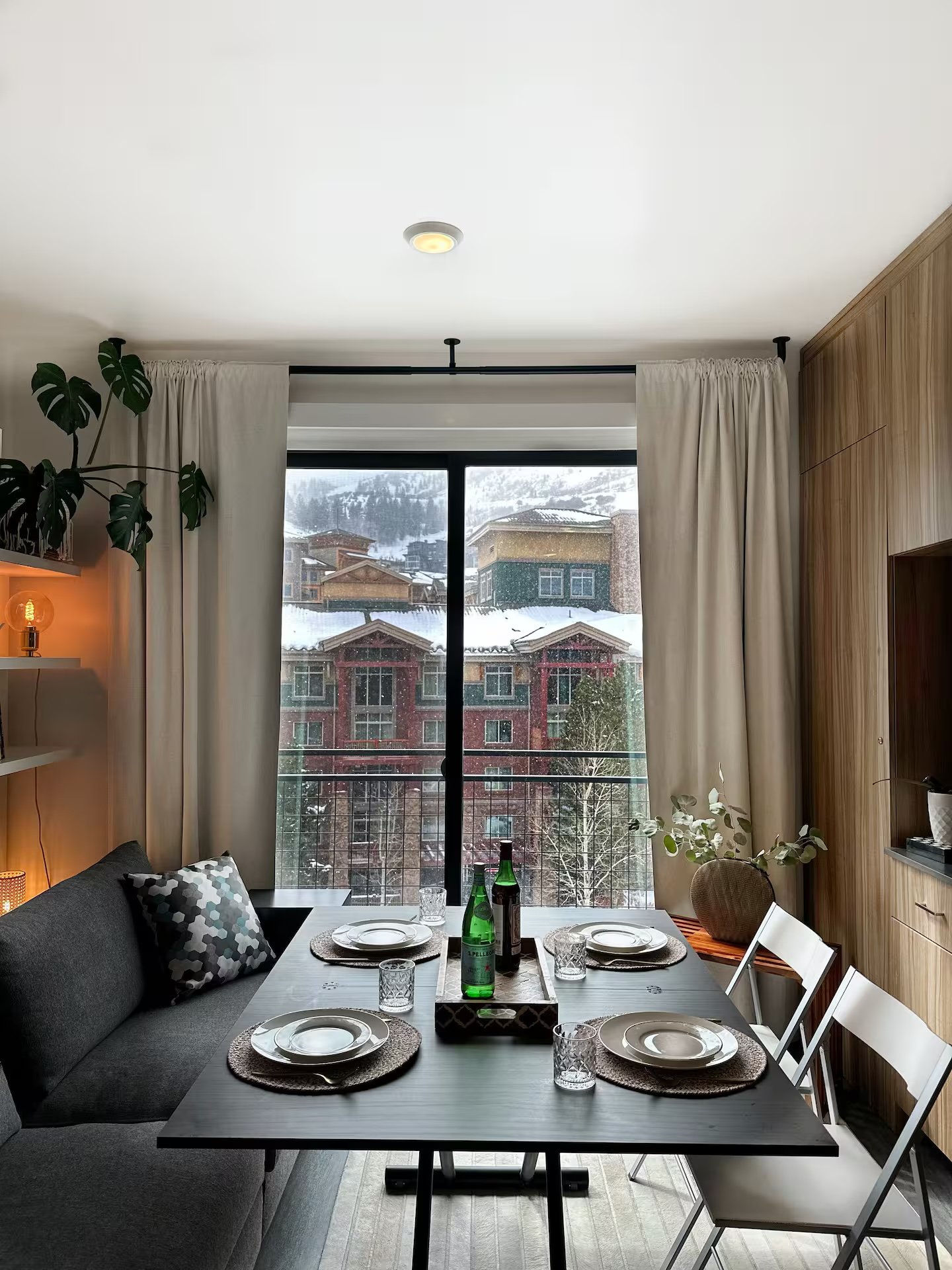 Dining area with mountain slope views through floor-to-ceiling window, table elegantly set for dinner