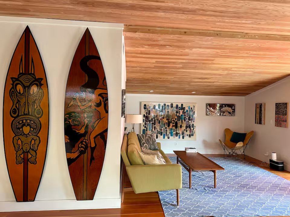 Living room with cedar ceiling, surfboard art, mid-century sofa, butterfly chair