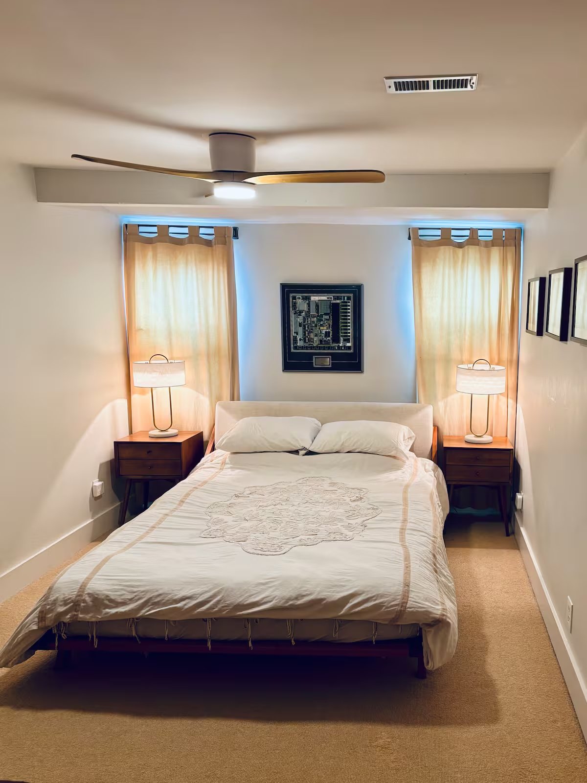 Queen bedroom with mid-century nightstands and warm pendant lamps