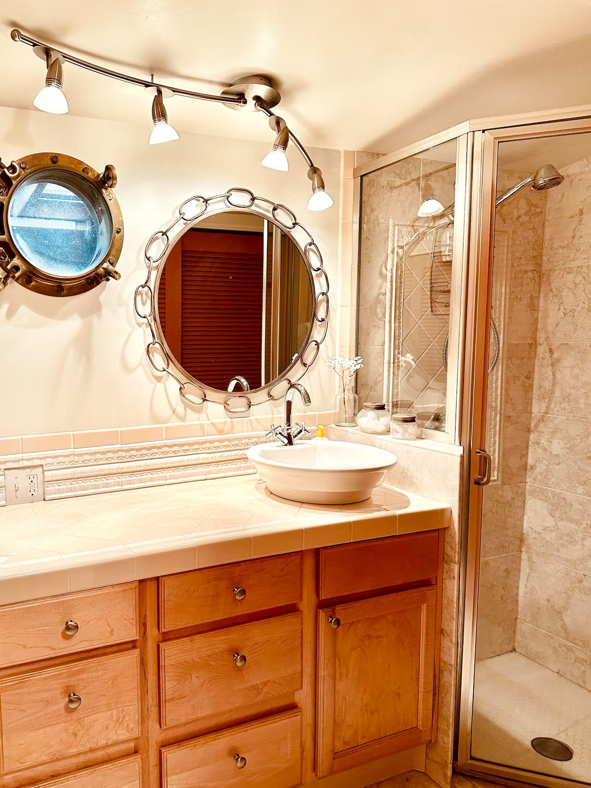 Bathroom with porthole mirror, vessel sink, cherry cabinets