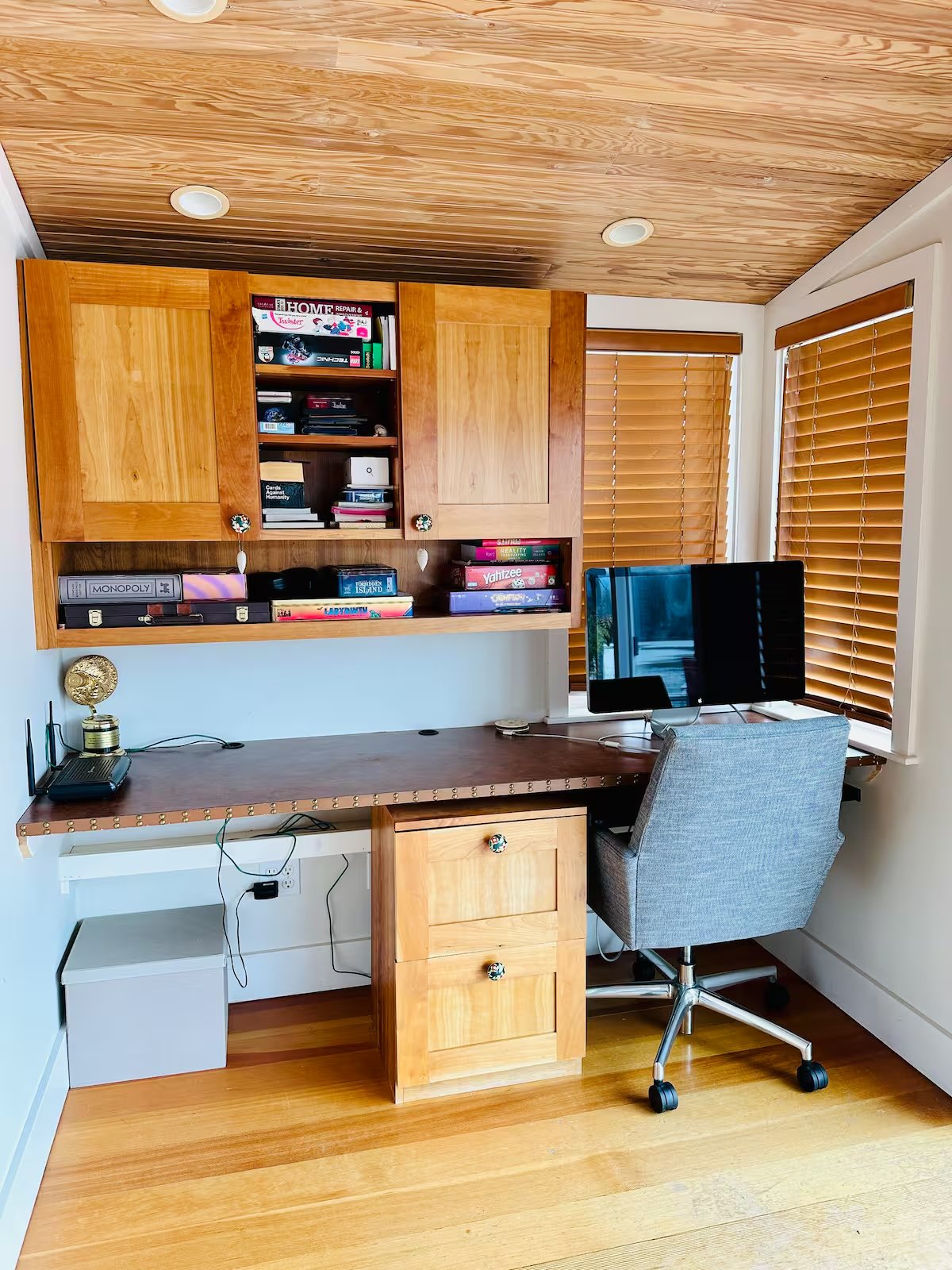 Built-in home office with dual monitors, books, cedar ceiling