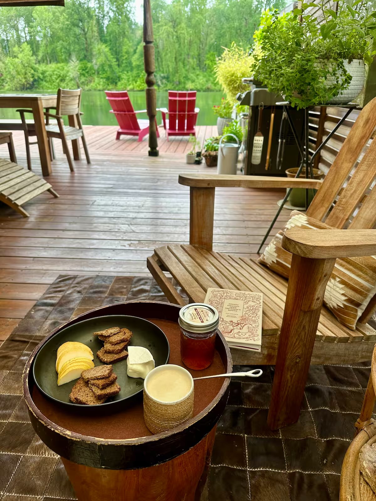Breakfast on a whiskey barrel — bread, cheese, honey — with red Adirondack chairs and green trees